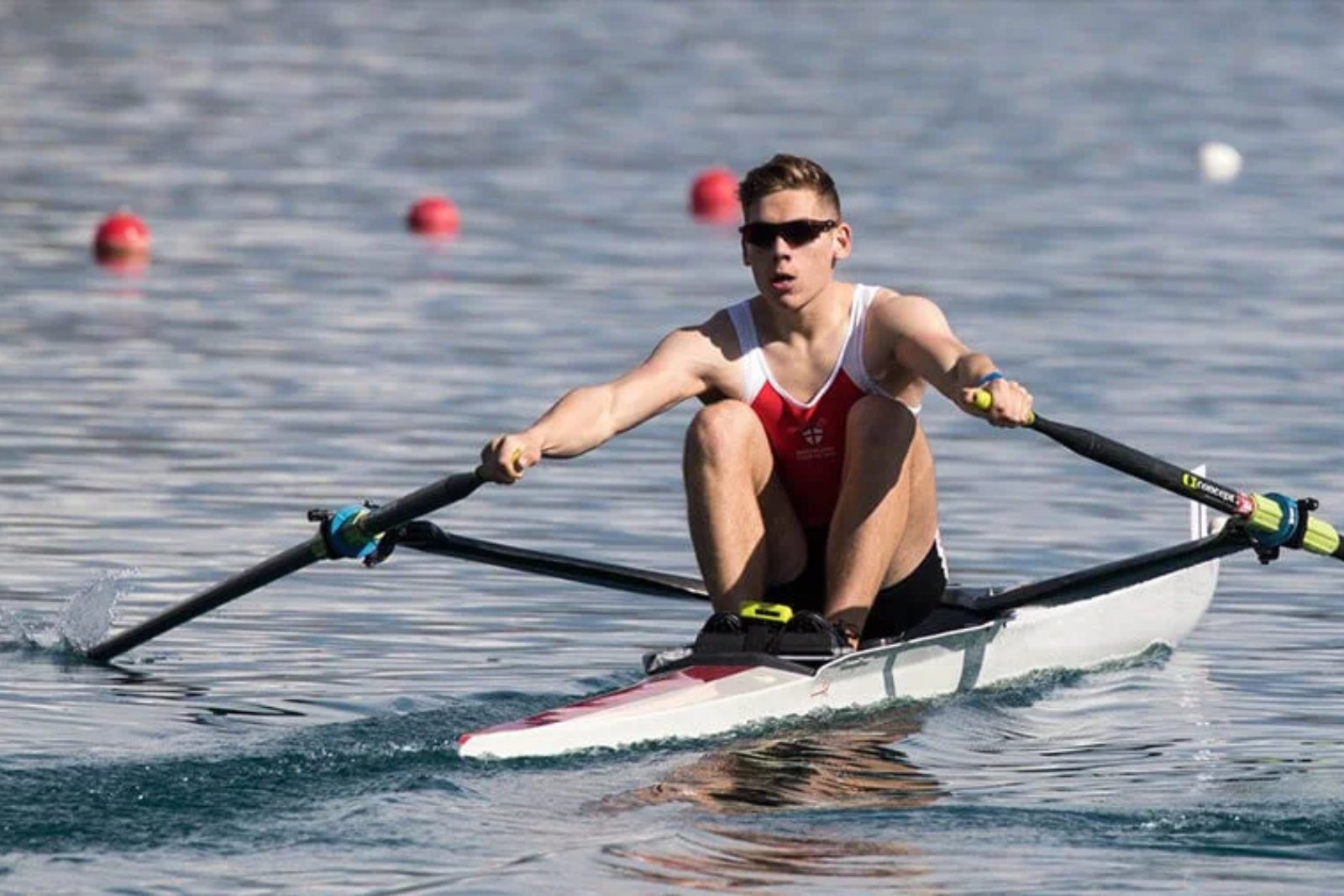 A rower in a single scull pulling hard down a buoyed racing course