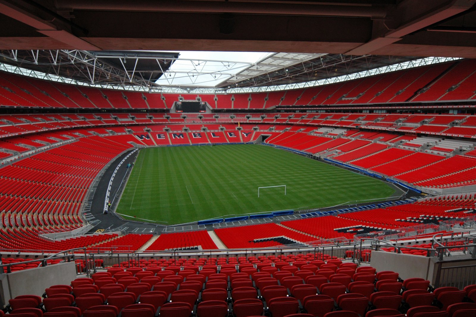 Wembley Stadium empty, with tiers of red seats around the pitch and WEMBLEY spelled out in the stands