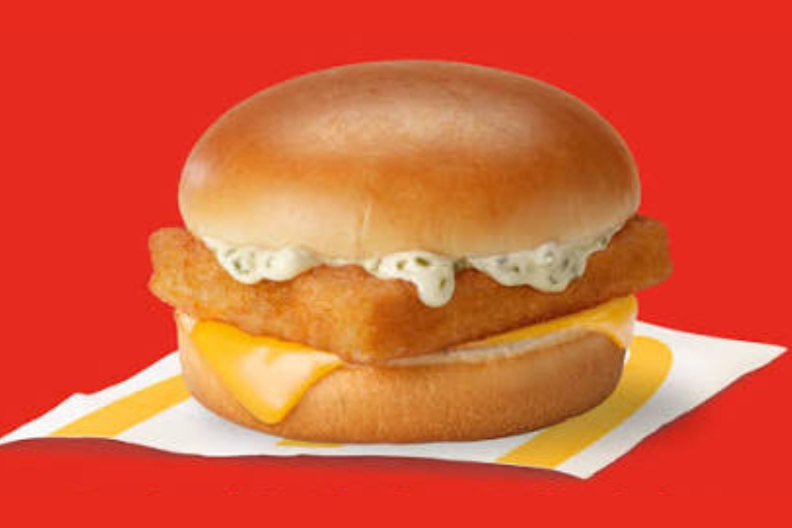 A McDonald's Filet-O-Fish sandwich with tartar sauce and cheese on a red background
